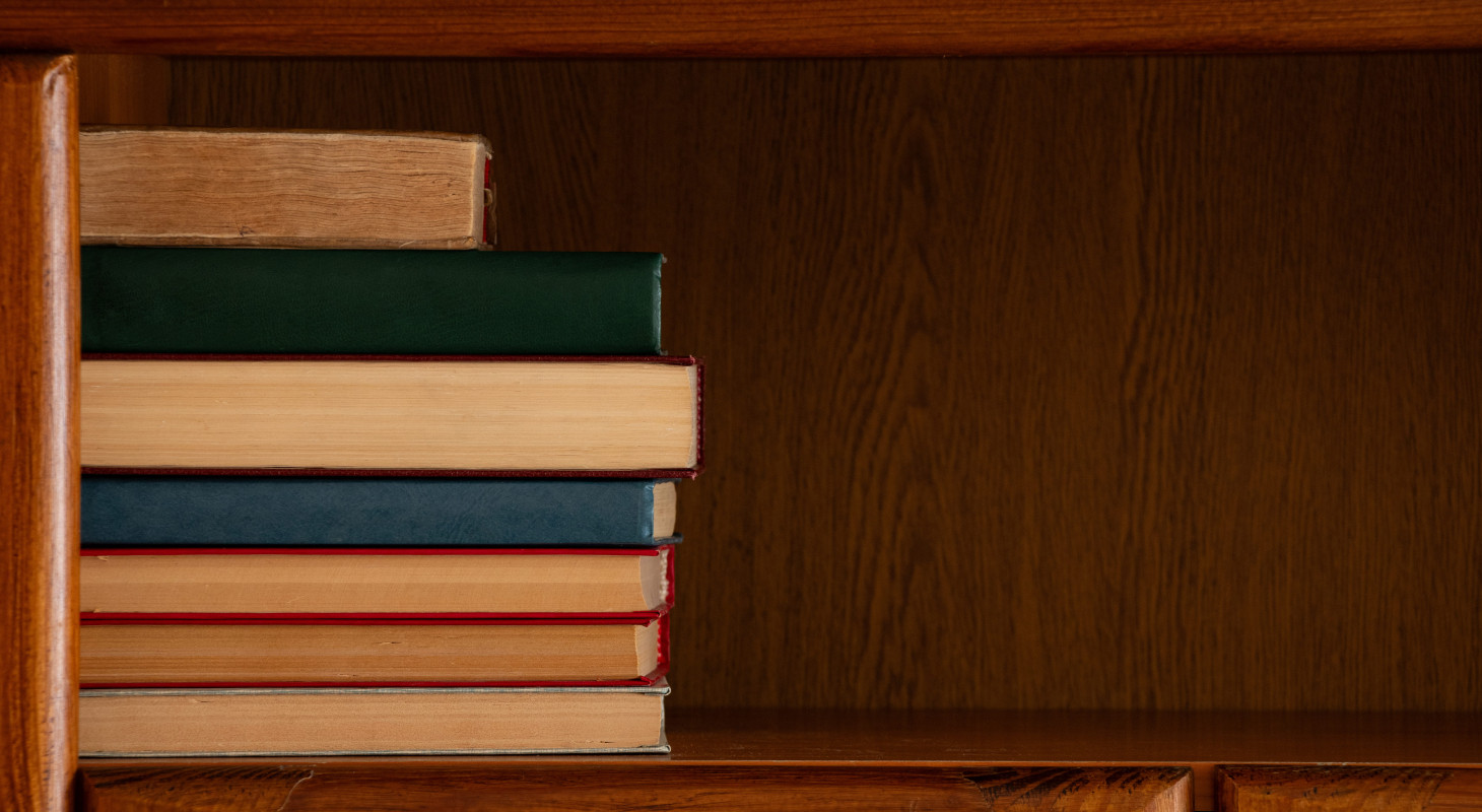 collection of books on a wooden shelf in cabinet