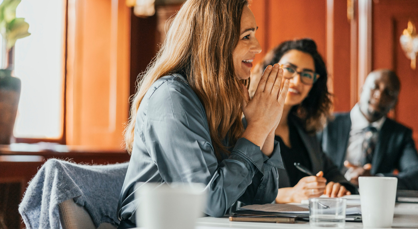 smiling businesswoman with hands clasped in meeting