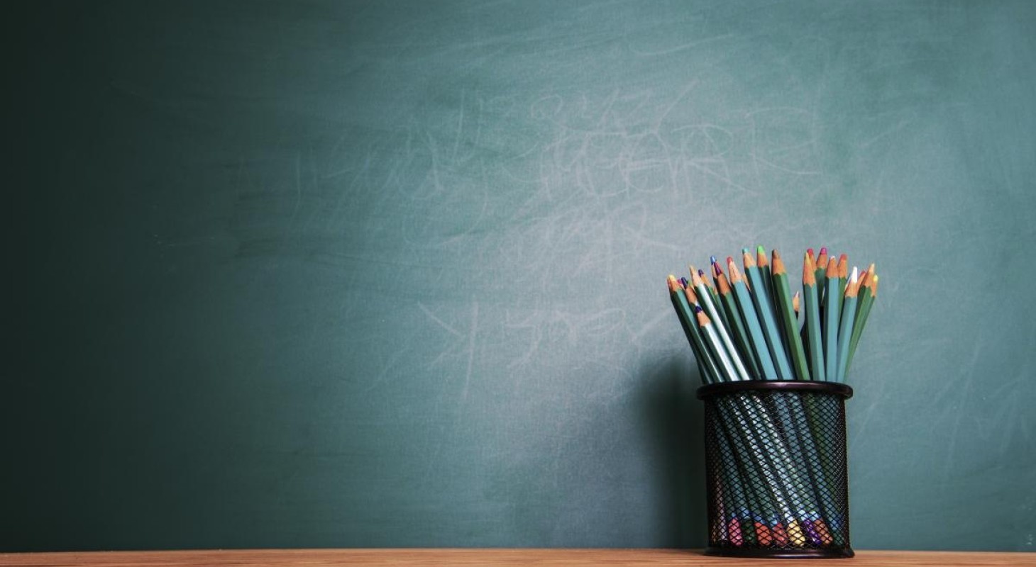 colored pencils in a black cup in front of green chalkboard