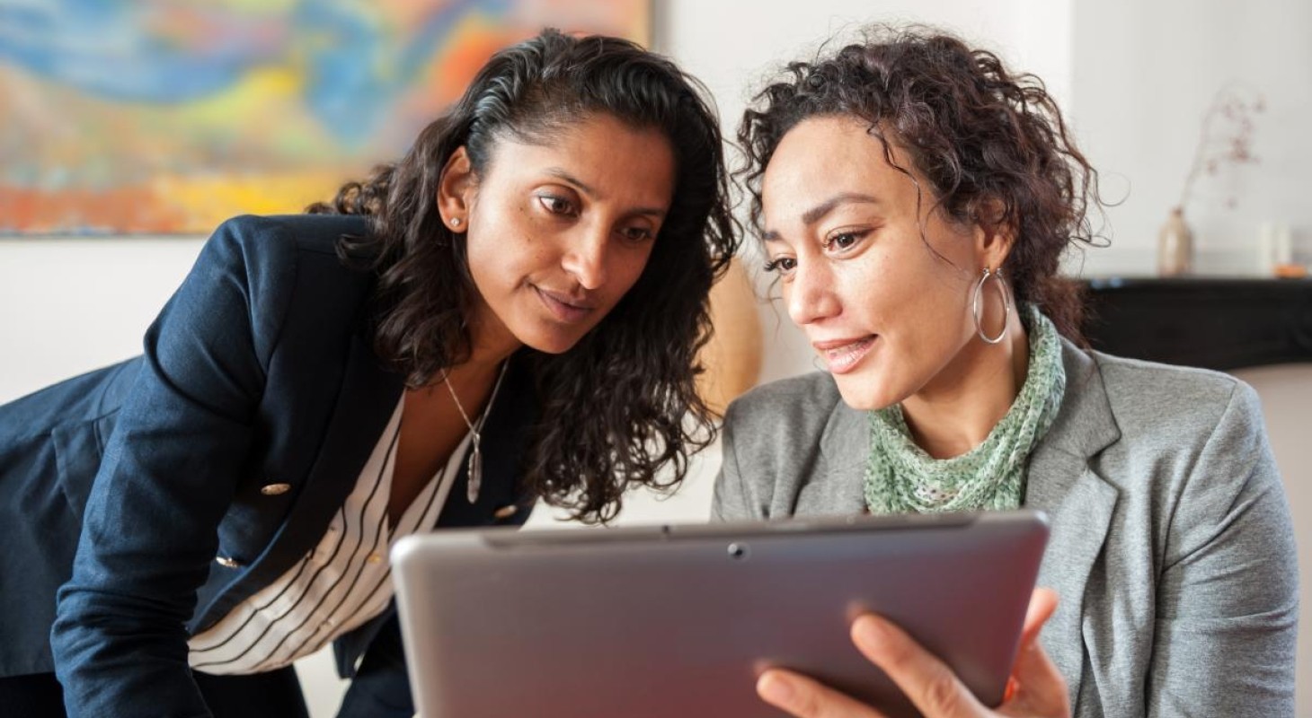 two women looking at a tablet