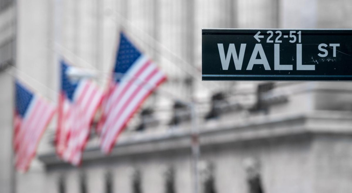 wall street sign with flags blurred in background