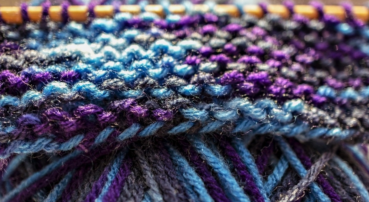 purple blue and gray yarns woven on knitting needle