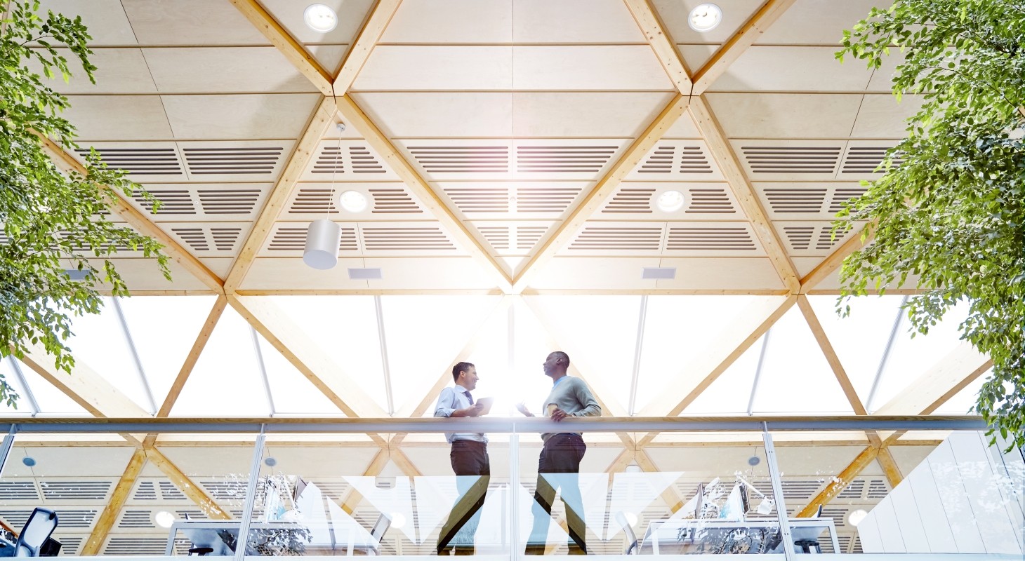 two male colleagues standing at glass railing in modern office