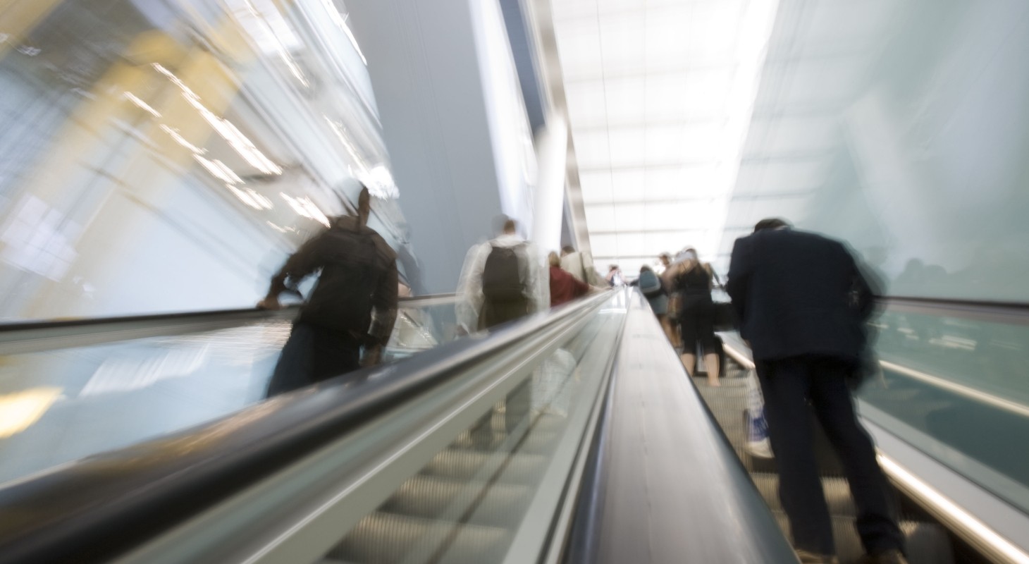 blurred image of business people riding an escalator