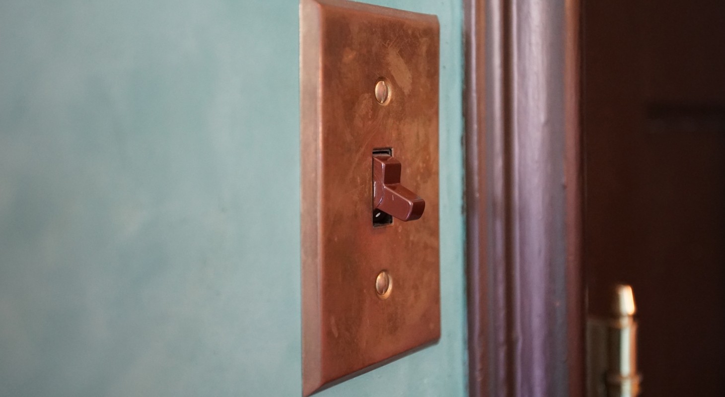 copper colored light switch on turquoise wall