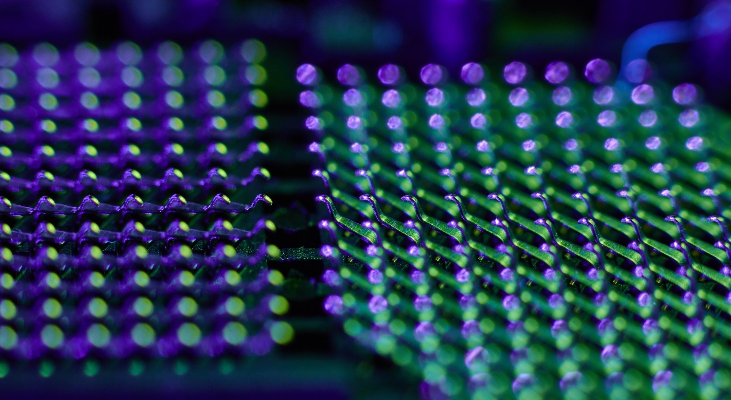 extreme closeup of cpu land grid array lit with purple and green lights