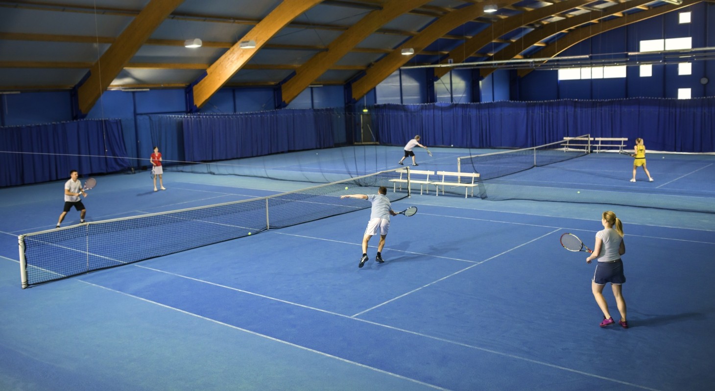 indoor game of mixed doubles tennis on light blue court