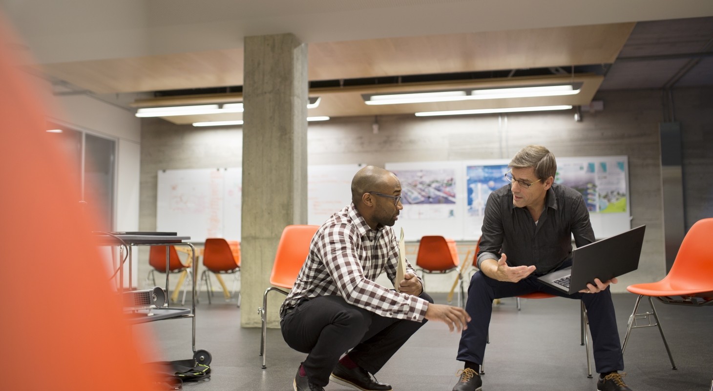 two men having concerned discussion in empty meeting room