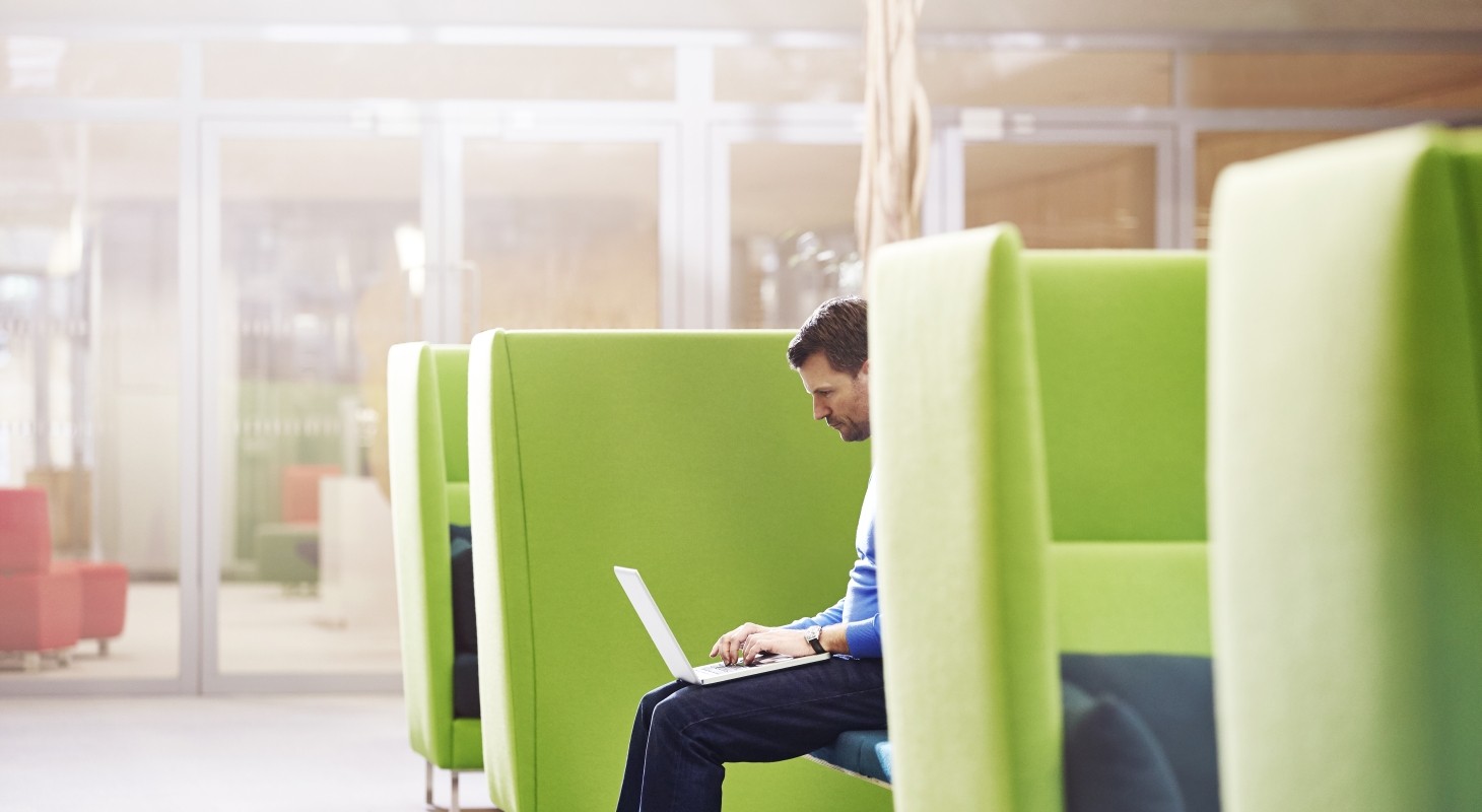 man working on laptop in lime green booth