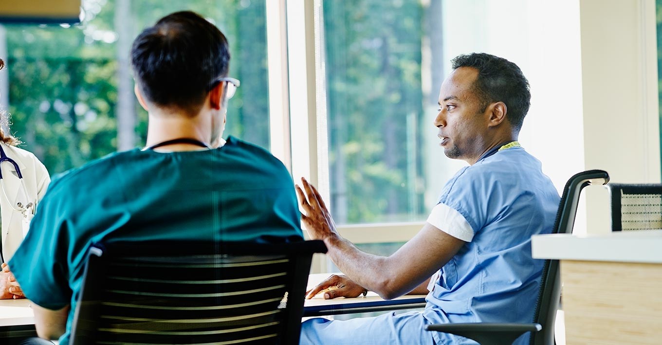 male nurse talking to colleagues in a meeting room