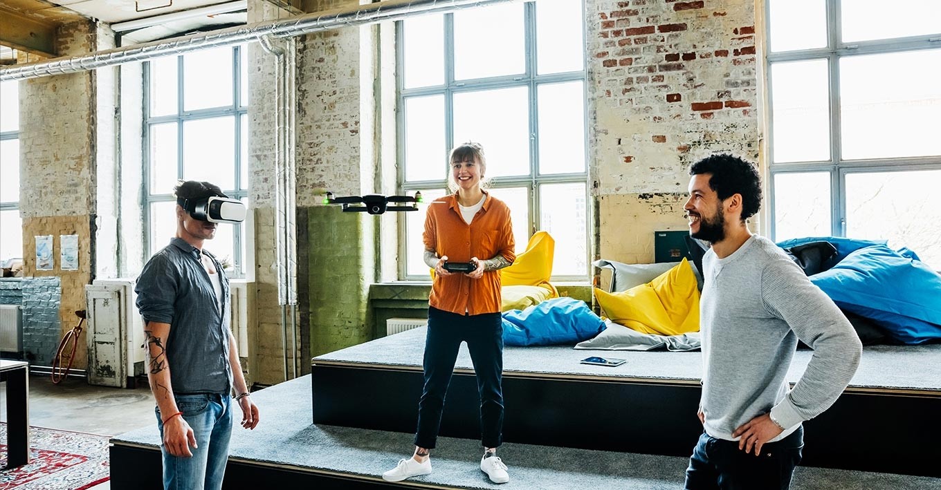 three people looking a drone flying in the middle