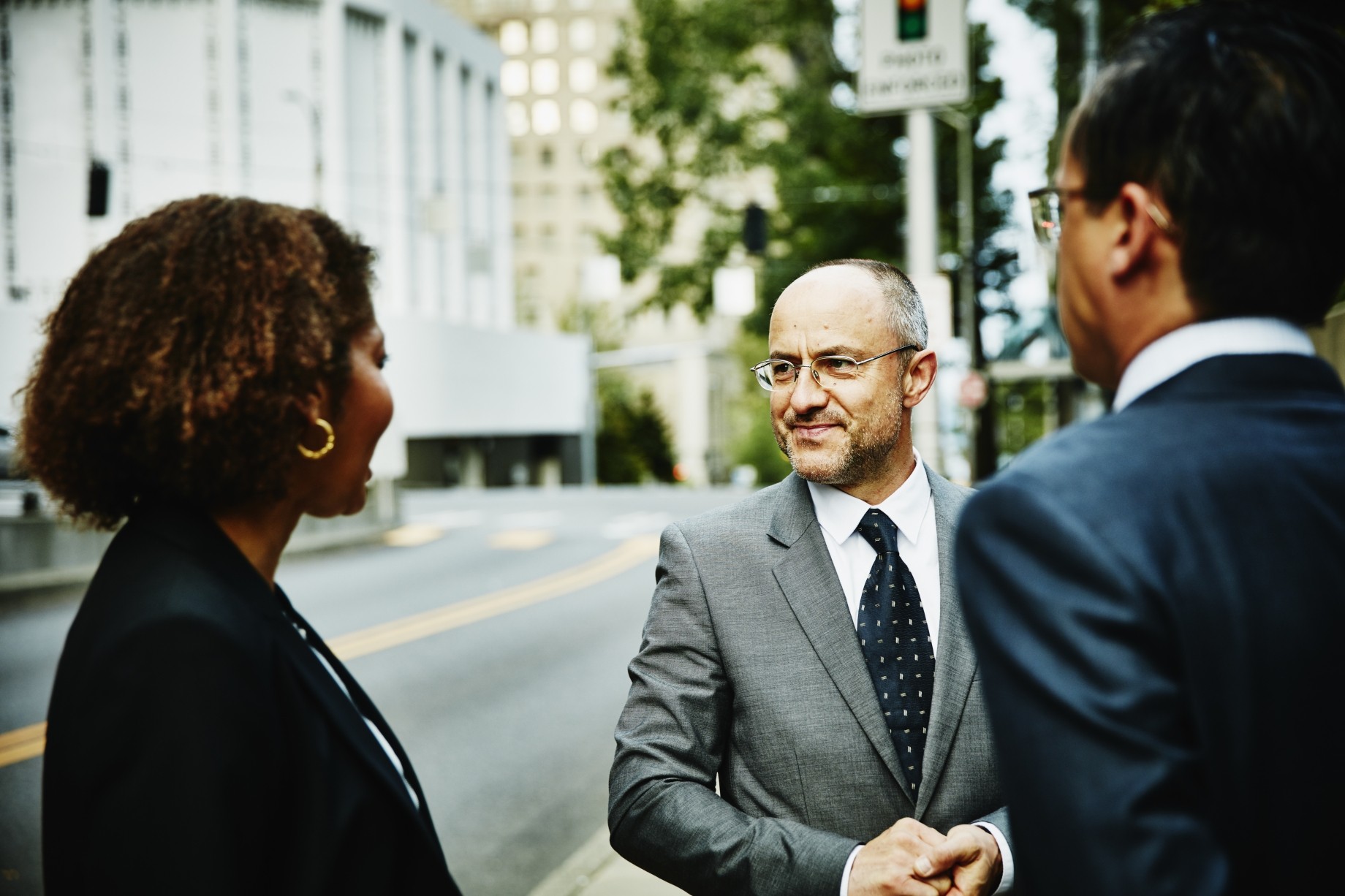 three colleagues in discussion on sidewalk