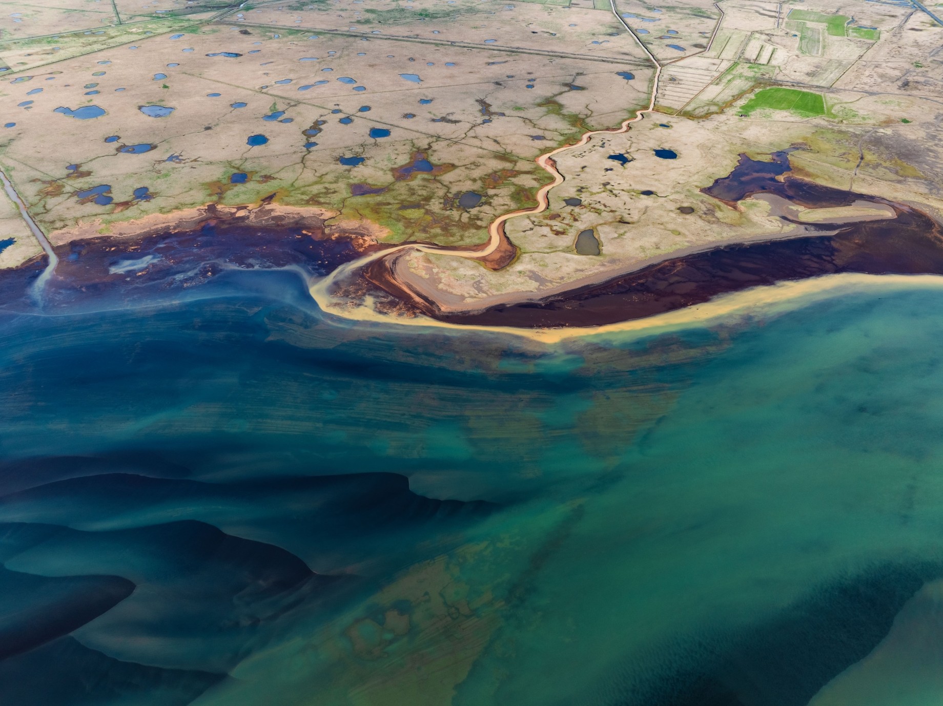 aerial shot of a coastal plain filled with blue ponds