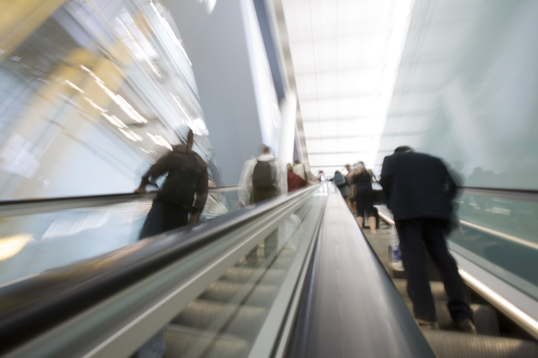 blurred image of business people riding an escalator