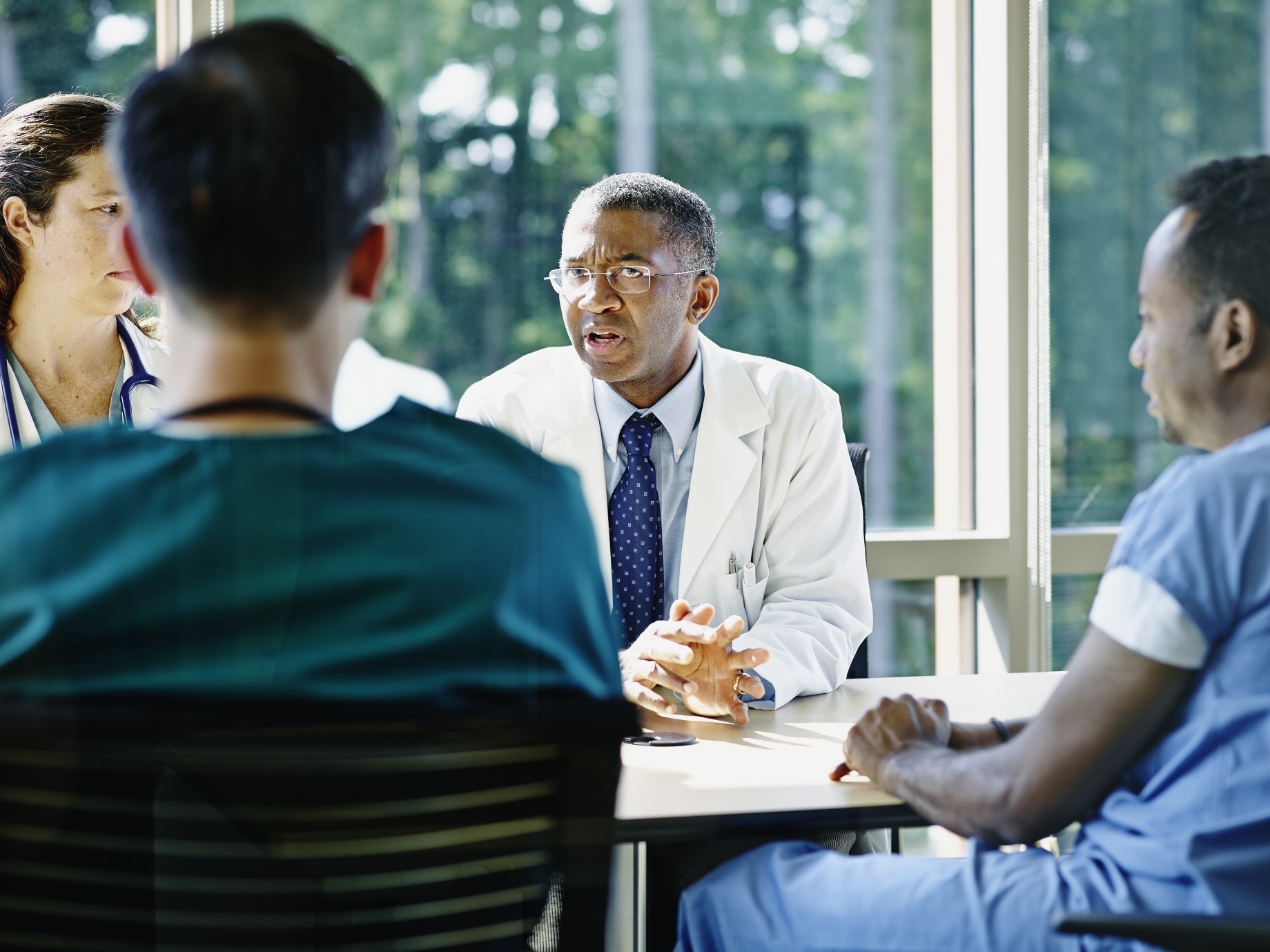 mature male doctor leading medical team meeting