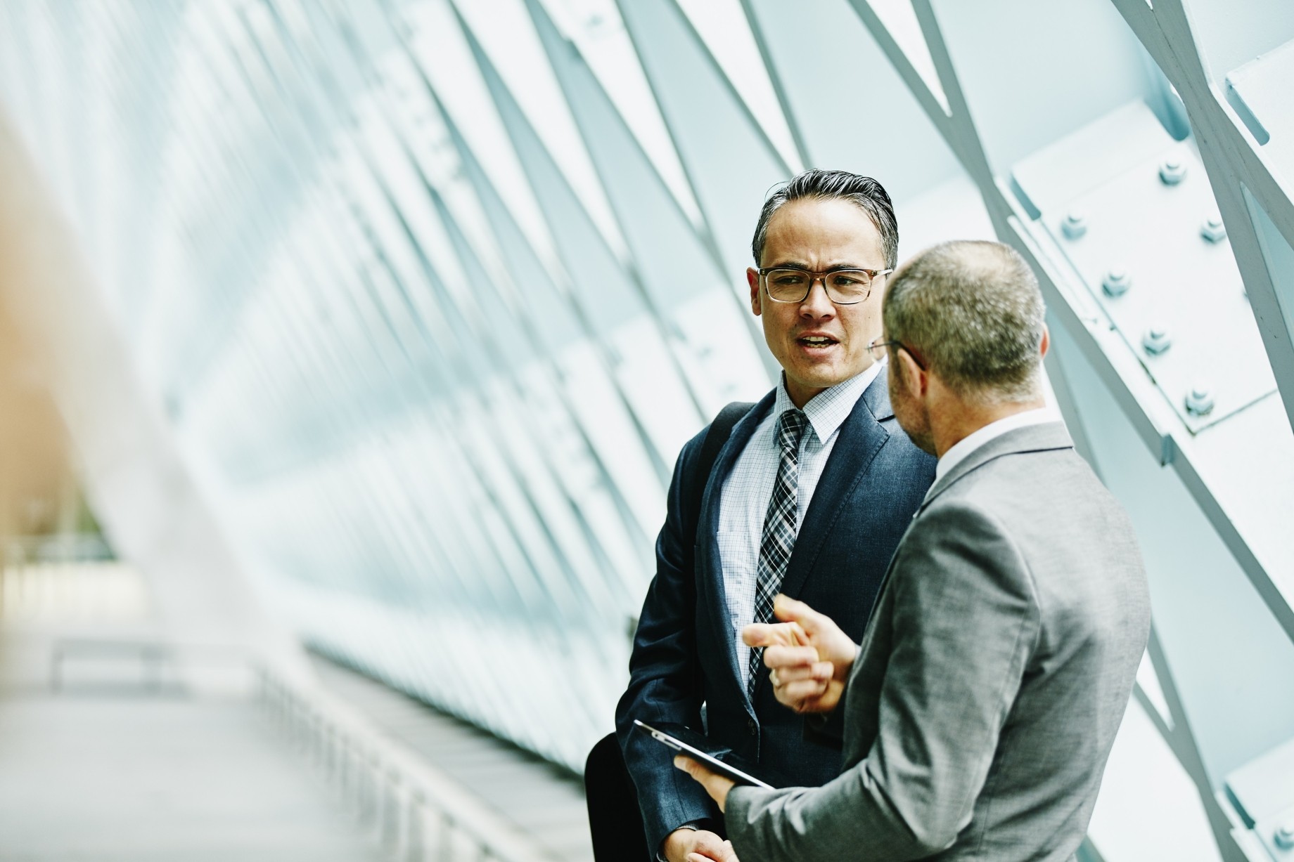 two businessmen discussing data on digital tablet