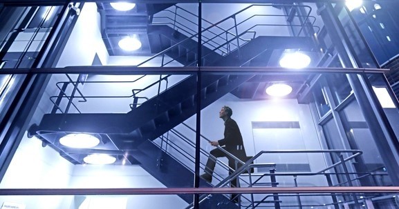 man climbing stairs in glass high rise building at night