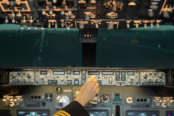 female airline pilots hand on control panel