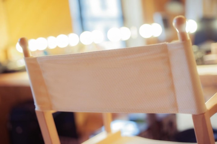 beige directors chair with makeup lights in background