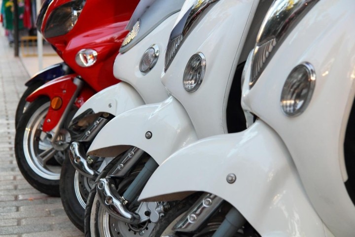 parked row of three white scooters followed by one red scooter