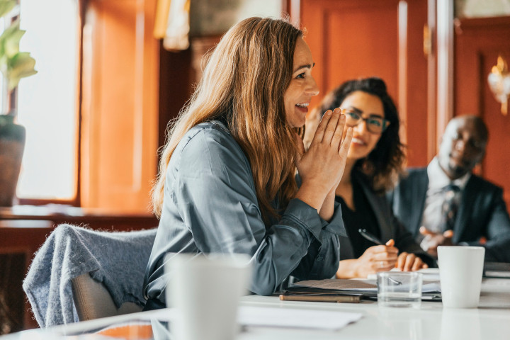 smiling businesswoman with hands clasped in meeting
