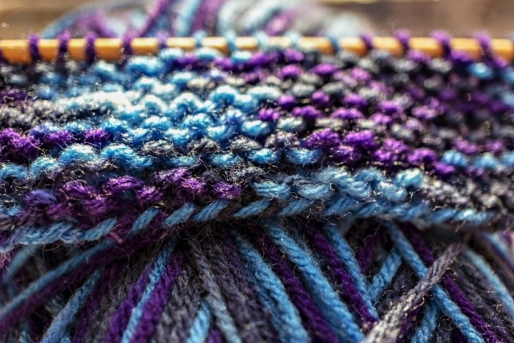 purple blue and gray yarns woven on knitting needle