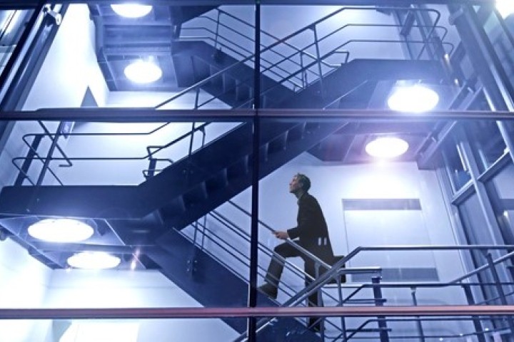 man climbing stairs in glass high rise building at night