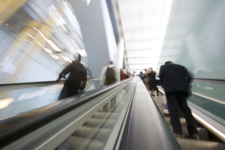 blurred image of business people riding an escalator