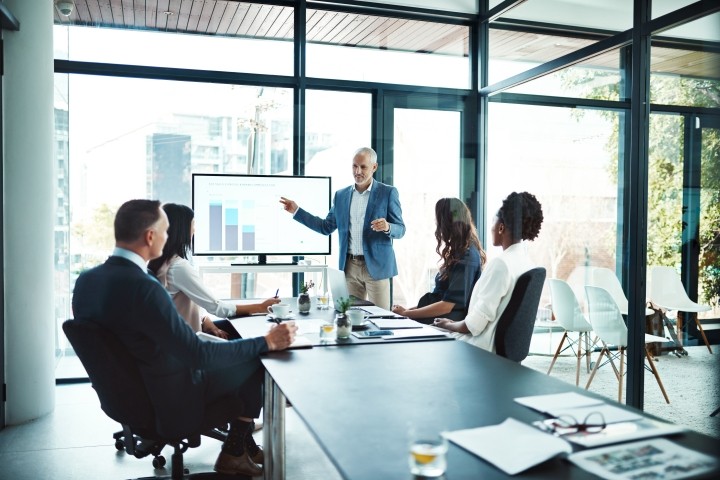 man giving presentation to group of people in glass room