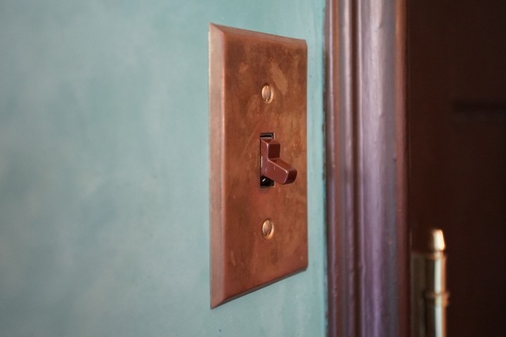 copper colored light switch on turquoise wall
