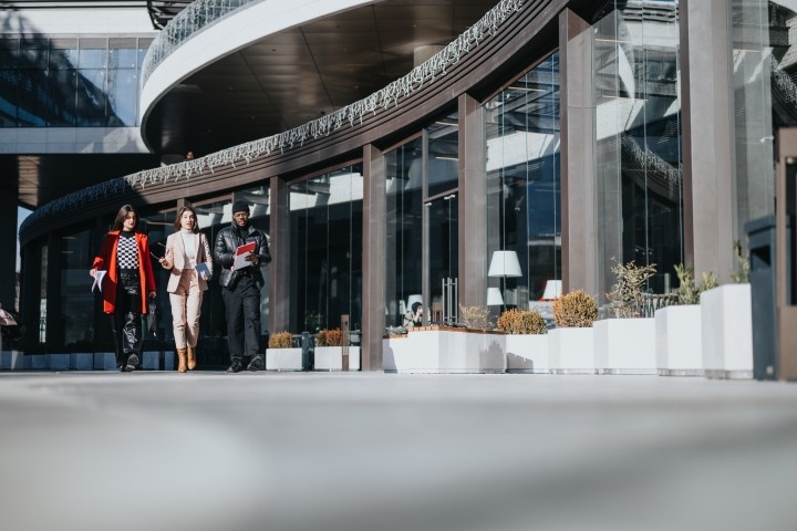 three colleagues walking together outside a modern office building