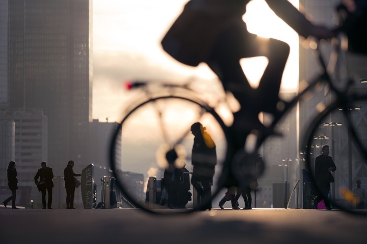 Silhouette of business person on bicycle on busy street