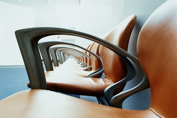 row of empty brown leather chairs with black arms