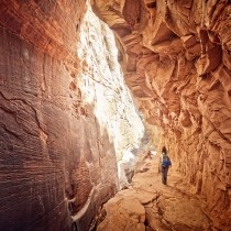 female hiker walking through red canyon