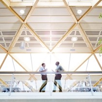 two male colleagues standing at glass railing in modern office