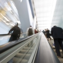 blurred image of business people riding an escalator