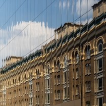 old office building reflected in the facade of new glass building