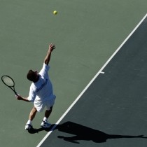 male tennis player serving on dark gray and green court