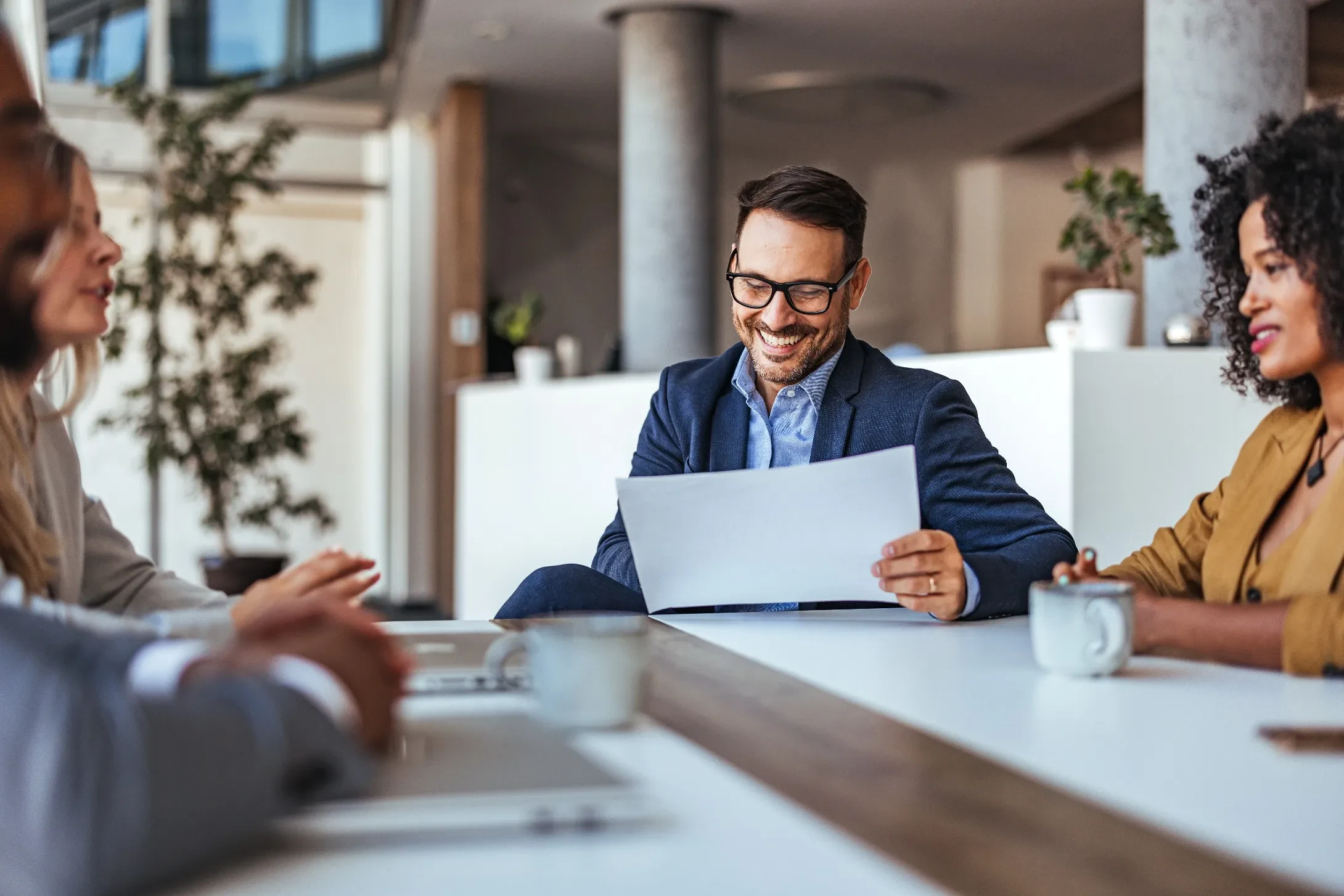 people speak together at a conference table reviewing documents