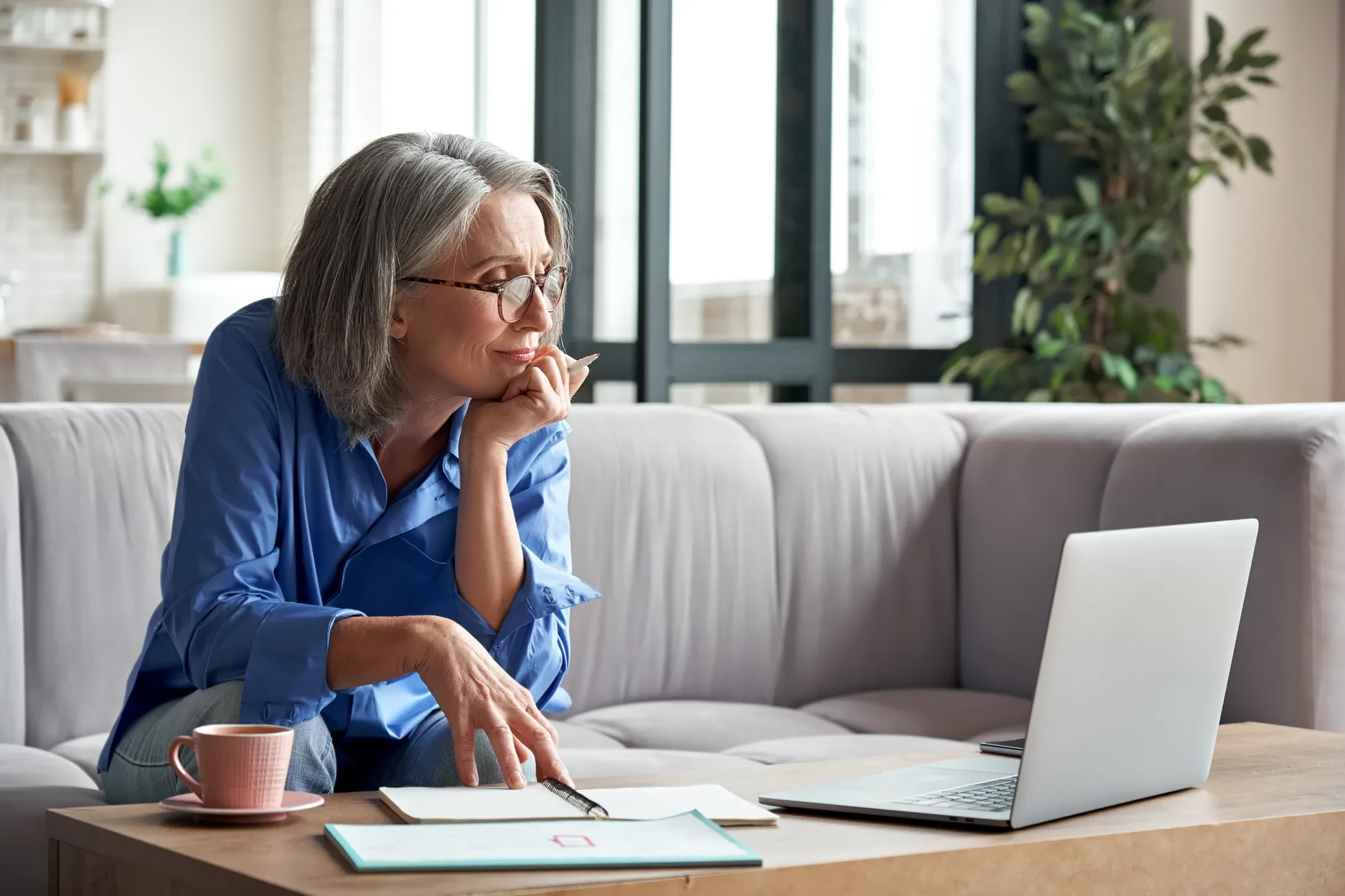 female director with gray hair and blue shirt attending online meeting from home