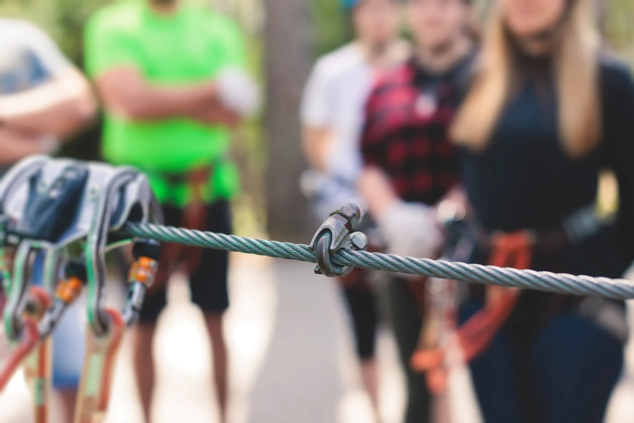 closeup of ropes course equipment with work team blurred in background